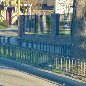 short metal border fence surrounds a parking strip, with a matching tall fence behind it